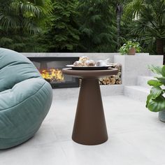 a chair and table in front of a fire place with potted plants next to it