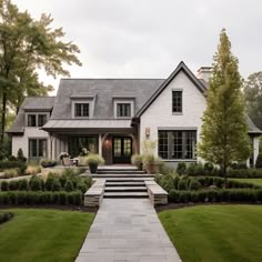 a white house with steps leading up to the front door and landscaping in front of it