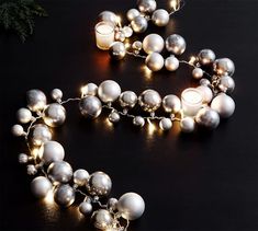 a silver and white beaded necklace with lights on the beads is laying on a black surface