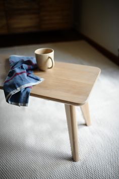 a wooden table with a coffee cup on it and a blue towel draped over it