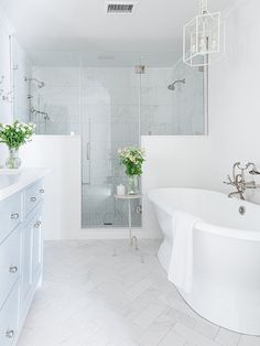 a white bathroom with a tub, sink and shower