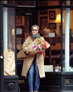 a woman walking out of a store holding flowers