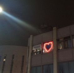 a building with a heart sign on it's side in the dark night time