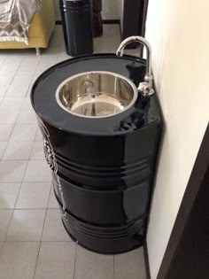 a black barrel sink sitting next to a white wall in a room with tile flooring