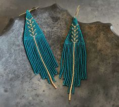 two pairs of turquoise beaded earrings with gold accents on top of a stone slab