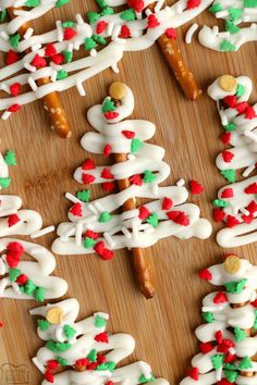 christmas cookies are arranged on a wooden board with white icing and red green and gold sprinkles