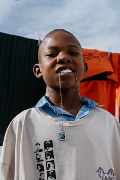 a young boy wearing a t - shirt with a chain attached to his mouth