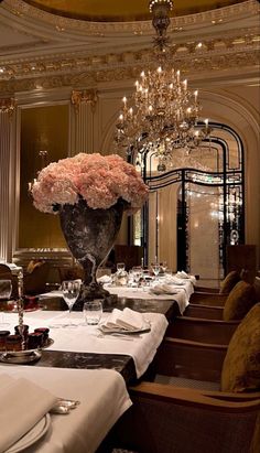 a fancy dining room with chandelier and flowers in the centerpieces on the table