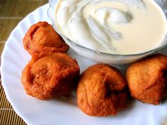 some food is sitting on a white plate and next to a bowl of yogurt