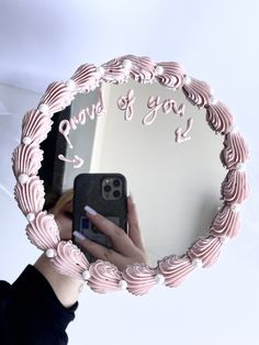 a woman taking a selfie in front of a mirror with pink icing on it