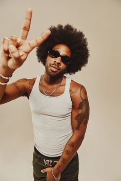 a man with an afro is making the peace sign while wearing sunglasses and a tank top