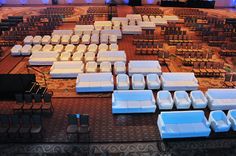 rows of white couches and chairs are arranged on the floor in front of a stage