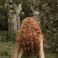 a woman with red hair walking down a path