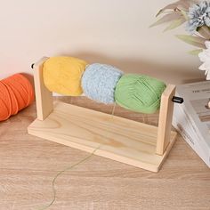 three balls of yarn sitting on top of a wooden stand next to two skeins of yarn