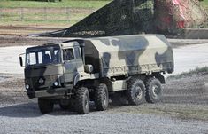 an army truck driving down a gravel road