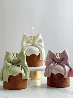 three cakes decorated with bows on top of each other and one has a candle in the middle