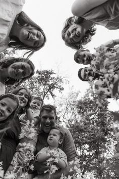 a group of people standing around each other in the middle of a tree filled forest