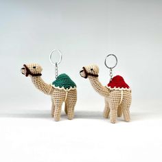 two crocheted camels with hats on their heads, one holding a keychain