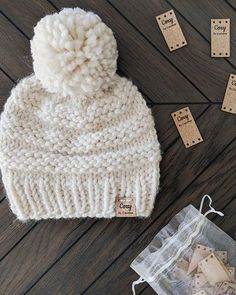 a knitted hat sitting on top of a wooden floor next to tags and string