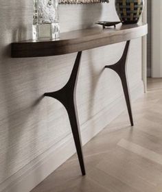 a long console table with two vases on it's sides in front of a white wall