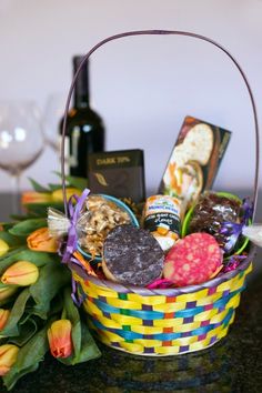 a basket filled with lots of different types of food next to a bottle of wine