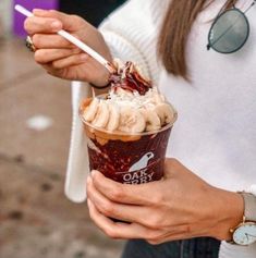 a woman is holding a cup of ice cream