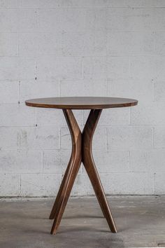 a round wooden table sitting in front of a white brick wall