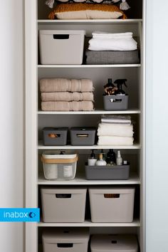 an organized closet with baskets, towels and other items on it's shelfs