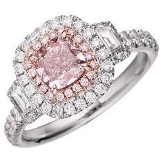 a pink diamond ring with two baguets on the band and diamonds around it