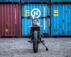 a motorcycle is parked in front of some shipping containers on the ground with it's handlebars down