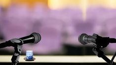 two microphones sitting next to each other on top of a table in front of a purple background