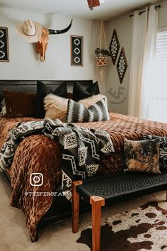 a bed sitting in a bedroom next to a window covered in blankets and throw pillows