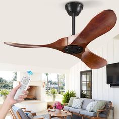 a person holding a remote control up to a ceiling fan