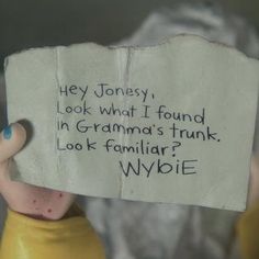 a close up of a person holding a piece of paper with words written on it