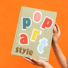 a person holding up a pop art book with the title pop art style written on it