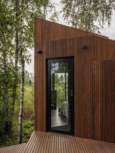 a wooden building with glass doors on the outside and trees in the backgroud