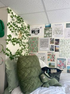 a bed with green pillows and pictures on the wall above it, along with a stuffed animal