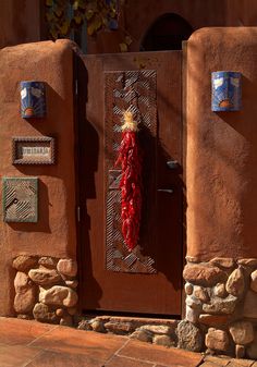 a red pepper hanging on the side of a door in an adobe - style building