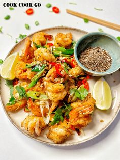 a white plate topped with shrimp and veggies next to a bowl of seasoning