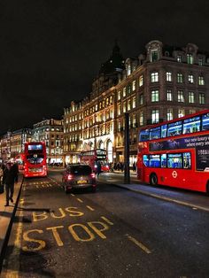 red double decker buses driving down the street at night