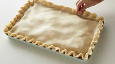 a person is placing an uncooked pie crust on top of the baking sheet