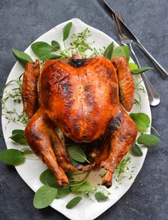 a whole chicken on a plate with leaves