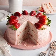 a cake with strawberries on top is cut in half and sits on a pink plate