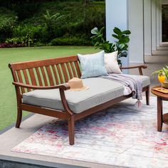 a wooden bench sitting on top of a white rug next to a table with flowers