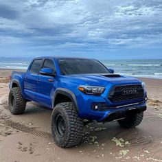 a blue truck parked on top of a sandy beach