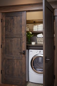 a washer and dryer in a small room with wooden doors leading to the bathroom