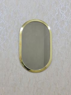 a mirror that is on the wall in front of a white and gold wallpaper