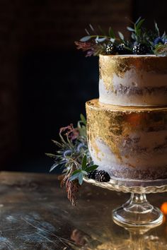 a three layer cake sitting on top of a table next to an orange and blackberries