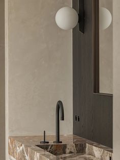 a bathroom sink sitting under a mirror next to a wall mounted faucet with two lights on it