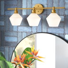 a bathroom with a round mirror and three lights on the wall next to a blue tiled wall